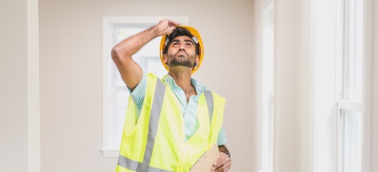 A home inspector looking up inspecting the interior of a house